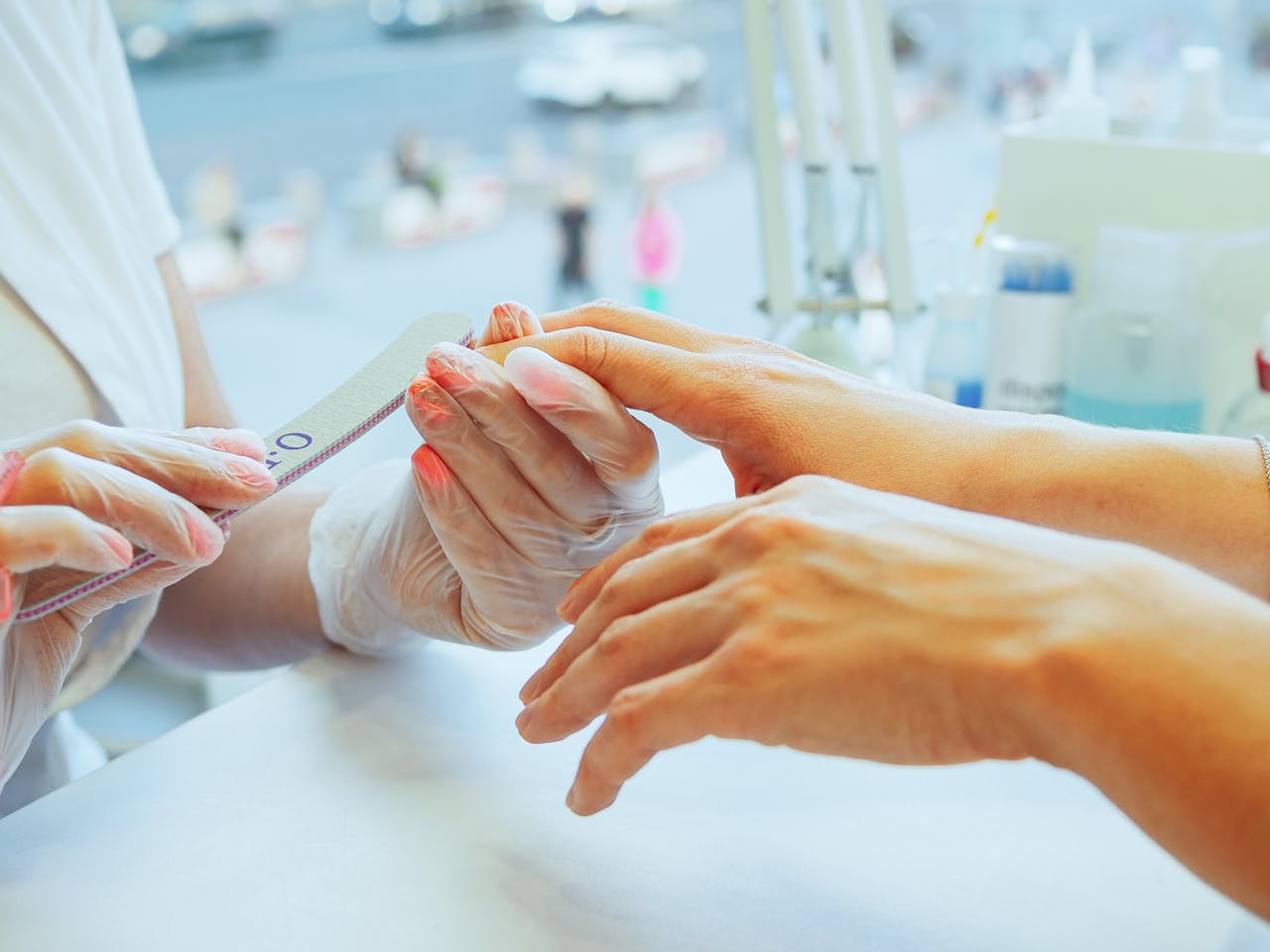 our-experience Close-up of a manicurist performing a nail file treatment on a customer's hand in a salon.