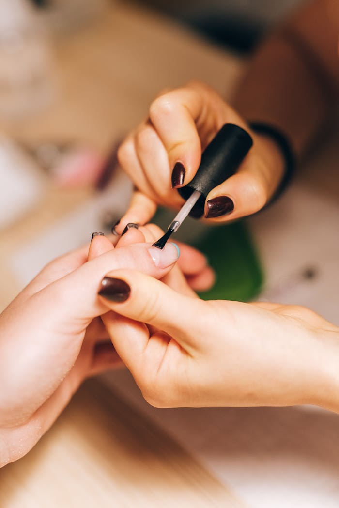 gallery-2 Close-up of a manicurist applying nail polish during a professional manicure session.