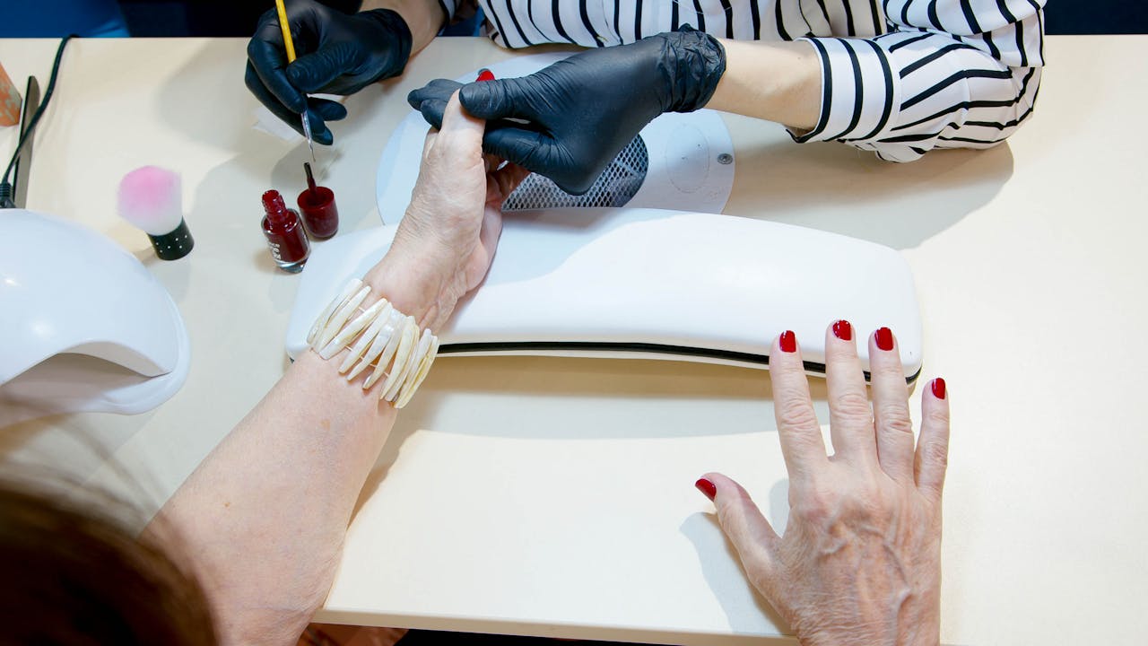 Top view of a professional manicure session with red nail polish application in a modern salon.